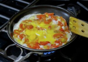Cooking the scrambled eggs with tomatoes.