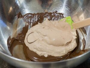 Adding melted chocolate to whipped cream.