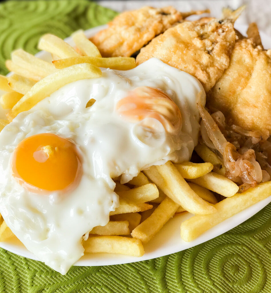Chilean fried fish a lo pobre, with fries, sauteed onions and fried eggs.
