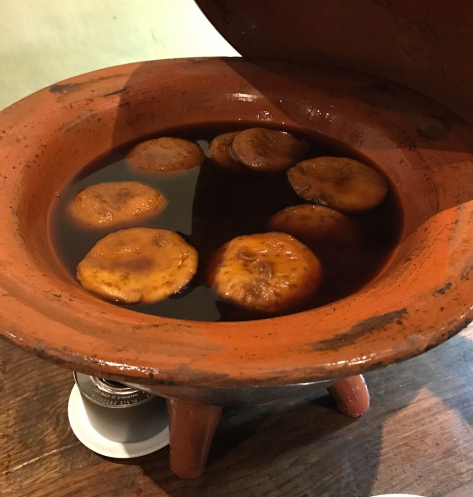 Chilean Sopaipillas pasadas (in a molasses syrup) inside a terracota pot.