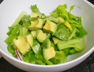 Bowl with celery, radishes and avocado.