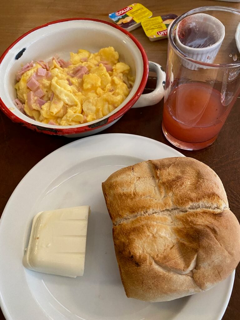 Chilean breakfast with fresh juice, scrambled eggs with ham, and marraqueta.